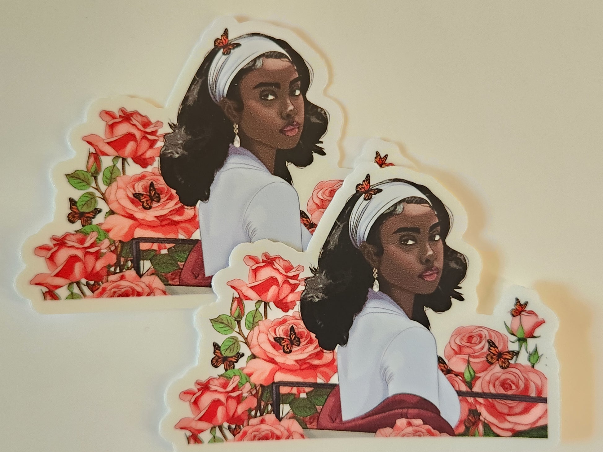 Two illustrated stickers of a woman with flowers and butterflies on a beige background